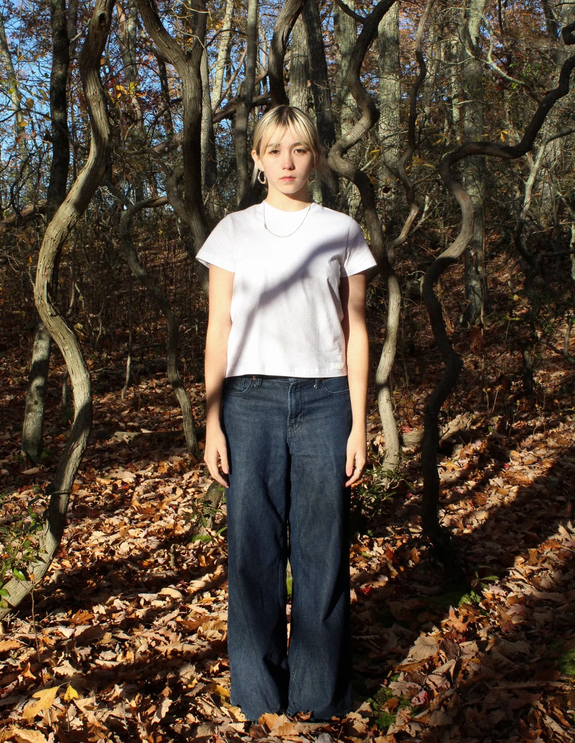 Person standing in a forest with autumn leaves